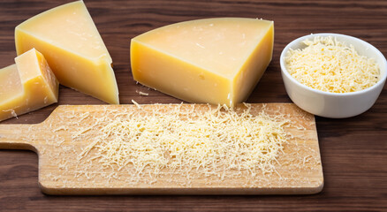 block of grated cheese on a wooden board and a grater in high resolution and sharpness