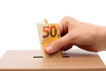 charity, savings and fundraising concept - close up of hand putting euro cash money into donation...
