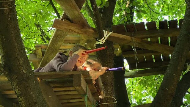 Closeup children full of wonder imagination play inside treehouse. Kids peer through toy spyglass, embarking on adventurous make-believe journey. Sibling bonding, joy childhood exploration and fantasy