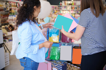 Rear view of a saleswoman and customer in creative art store. Pregnant woman shopping for school stationery