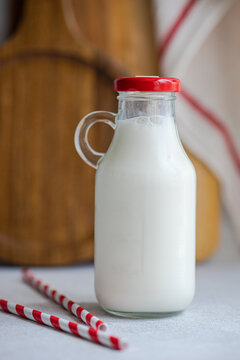 Raw cow milk in vintage bottle near drinking straws against blurred background