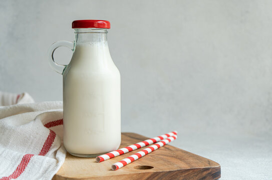 Raw cow milk in vintage bottle on cutting board near drinking straws and napkin