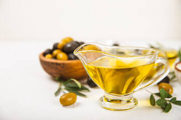 Olive oil in a bottle and gravy boat on the kitchen table. Oil bottle with branches and fruits of olives. Place for text. copy space. vegetable oil and salad dressing.