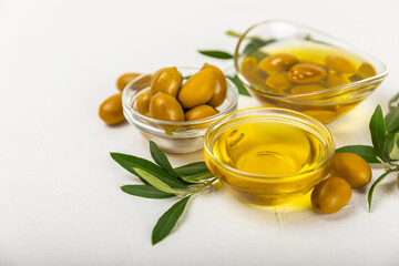 Olive oil in a bottle and gravy boat on the kitchen table. Oil bottle with branches and fruits of olives. Place for text. copy space. vegetable oil and salad dressing.