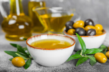 Olive oil in a bottle and gravy boat on the kitchen table. Oil bottle with branches and fruits of olives. Place for text. copy space. vegetable oil and salad dressing.