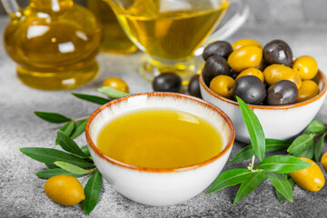 Olive oil in a bottle and gravy boat on the kitchen table. Oil bottle with branches and fruits of olives. Place for text. copy space. vegetable oil and salad dressing.