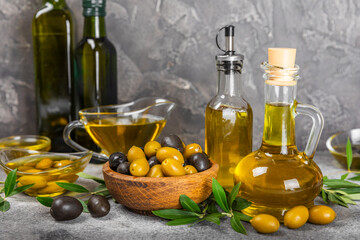 Olive oil in a bottle and gravy boat on the kitchen table. Oil bottle with branches and fruits of olives. Place for text. copy space. vegetable oil and salad dressing.