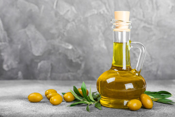 Olive oil in a bottle and gravy boat on the kitchen table. Oil bottle with branches and fruits of olives. Place for text. copy space. vegetable oil and salad dressing.