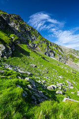 Fototapeta na wymiar Summer landscape of the Fagaras Mountains. View from the hiking trail from Lake Balea to Mount Negoiu. Amazing rock formations of the Carpathians, Romania.