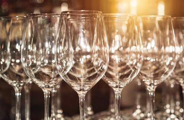 Close-up of wine or champagne glasses in row for abstract backgrounds restaurant. Empty clean glasses stands in row on rack bar prepared by bartender for event ceremony. Copy ad text space poster