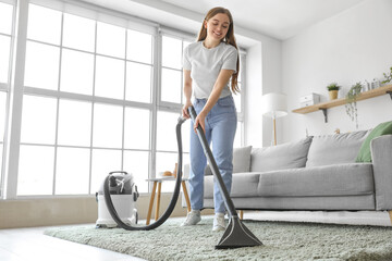 Young woman vacuuming carpet at home