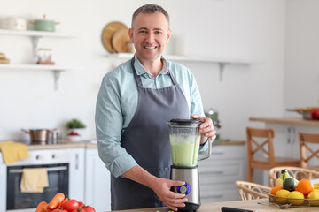 Mature man making smoothie with blender in kitchen