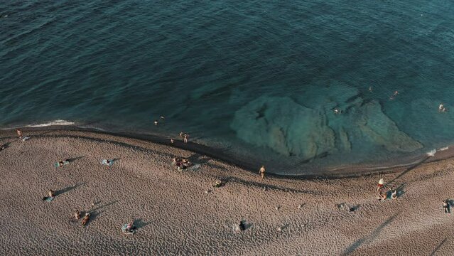Aerial view of pebble beach at the sea with large underwater rocks, drone footage. Rhodes, Greece.