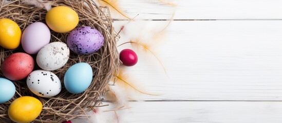 A top view of a white wooden background with a nest filled with colorful Easter eggs. copy space available.