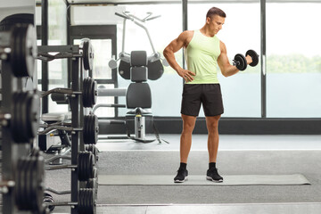 Bodybuilder in sportswear exercising with a dumbbell at a gym