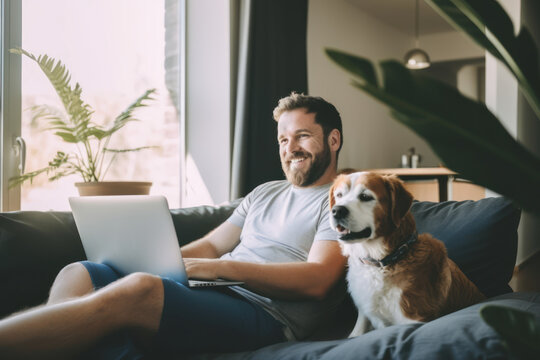 Balance between work and life: a young man teleworks on his sofa while watching television and enjoying the company of his dog