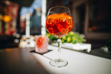 Glass of summer cocktail with ice on a sunny terrace table