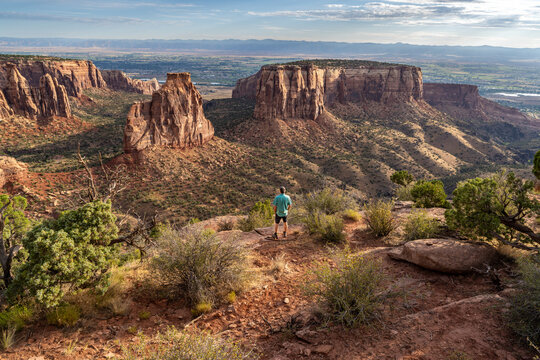 Mature Caucasian man, hiker, standing watching a natural occurring free standing pillar, Independence Monument, Colorado National Monument, Colorado