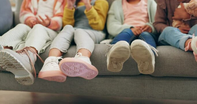 Family, feet and children watching tv in the living room while sitting on a sofa in their home together. Friends, legs and kids closeup on a couch in the living room to relax with entertainment