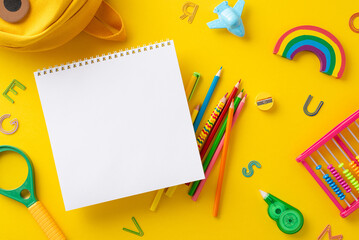 School supplies and gear composition. Top view shot capturing empty notepad page with backpack and...