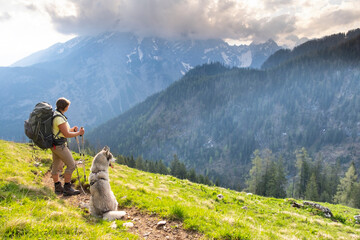 Sporty woman with a husky in Alp mountains. Traveling with a pet, friends, adventure concept