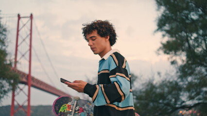 Smiling student walking mobile at coast closeup. Skater listening voice message