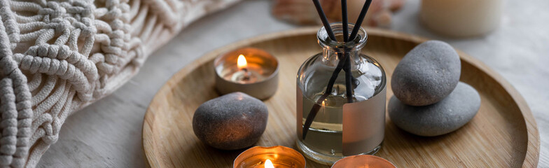 Apartment natural aroma diffusor ocean breeze fragrance. Banner. Burning candles on bamboo tray, cozy home atmosphere. Relaxation, detention zone in the living or bedroom. Stones, sea shells as decor