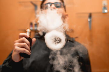 Fototapeta na wymiar Technician making a smoke ring with the vape.