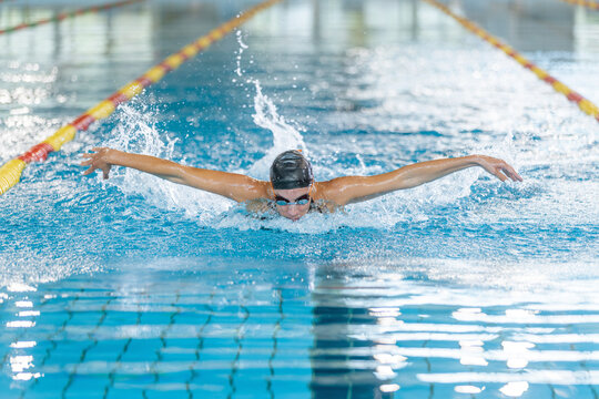 Front view of a powerful elite female swimmer competitor performing butterfly swim technique, arm stroke movements. Swim fly and dolphin kick concept.