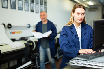 Woman in uniform, printing office worker, using computer, looking at display.