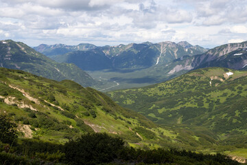 Fototapeta na wymiar Summer mountain landscape. View from the mountains to the valley. Travel, tourism and hiking on the Kamchatka Peninsula. Beautiful nature of Siberia and the Russian Far East. Kamchatka Krai, Russia.