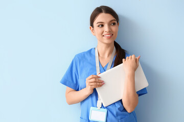 Female medical intern with laptop on blue background