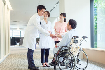 車椅子に乗った患者と握手をする医師