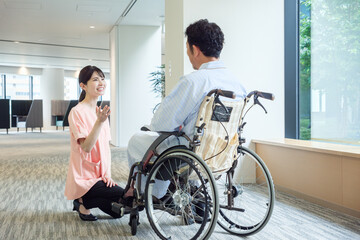 車椅子に乗った患者と会話をする看護師
