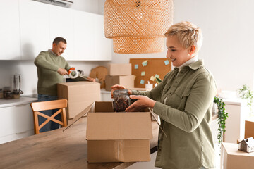 Mature couple packing things in kitchen on moving day