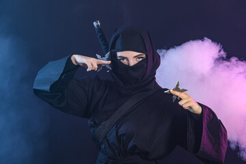 Female ninja with shurikens on dark background © Pixel-Shot