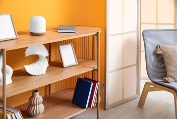 Wooden bookshelf with blank frames and decor in living room
