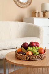 Wicker basket with fresh fruits on table in living room, closeup