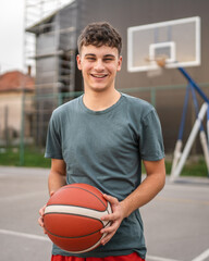 One caucasian teenager stand on basketball court with ball
