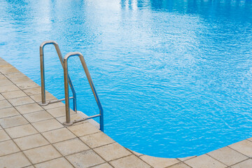 Swimming pool with selective focus on metal stairs and copy space for text.