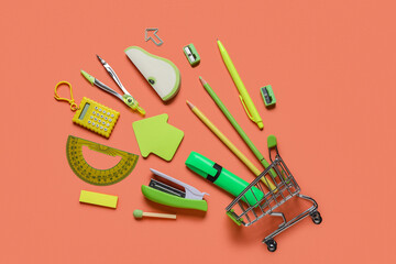 Shopping cart with different school stationery on orange background