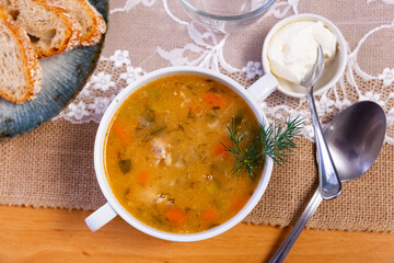 Soup with pickled cucumbers and pearl barley - rassolnik on wooden background.