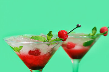 Glasses of fresh raspberry mojito on green background