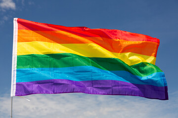 LGBT flag waving against the blue sky close-up