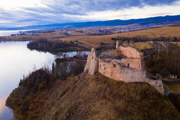 Picturesque aerial view of ruined medieval Czorsztyn Castle on hilltop on banks of Lake Czorsztyn at sunset, Poland