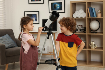 Cute little children using telescope to look at stars in room