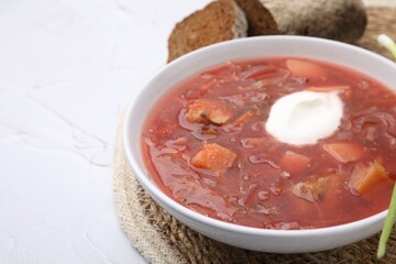 Tasty borscht with sour cream on white table, closeup. Space for text