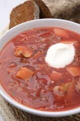 Tasty borscht with sour cream on table, closeup