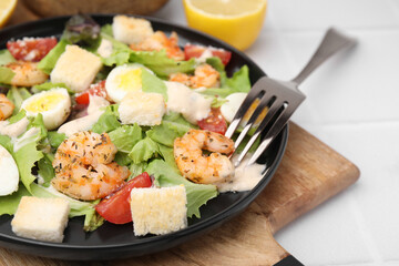 Delicious Caesar salad with shrimps and fork served on white table, closeup