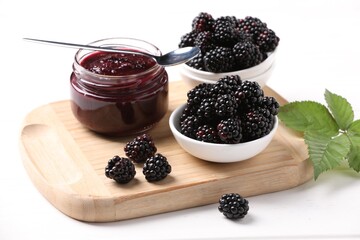 Fresh ripe blackberries, tasty jam and leaves on white wooden table